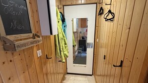 A narrow hallway with wooden walls, a door with a mirror, and a chalkboard with text. - Studio in the heart of the station - pets welcome (Le Lioran)