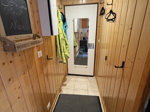 Un corridoio stretto con pareti in legno, una porta con uno specchio e una lavagna con scritte.