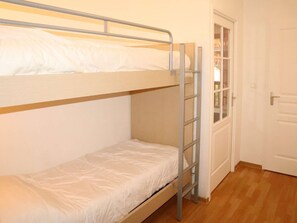 Ein Mehrbettzimmer mit einer Klapptreppe, einer Tür und einem Holzboden.