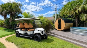 Ein Golfmobil mit überdachter Sitzecke, einem Holzfass und einem Schwimmbecken.
