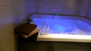 Una bañera con luz azul, dos vasos y una toalla marrón.