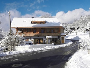 A two-story wooden building with a balcony, surrounded by snow-covered trees and a clear sky. - Charming chalet with WiFi - 18 guests (Samoëns)