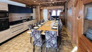 Una cocina moderna con electrodomésticos integrados, un comedor con sillas estampadas y un techo de madera.