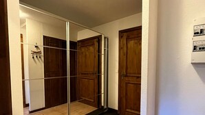 Huone, jossa on liukuovet, jotka ovat lasia, sekä puiset ovet ja laatoitettu lattia.