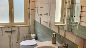 A modern bathroom with a toilet, sink, and mirror. - RAGGIO DI SOLE: STUDIO APARTMENT JUST A STONE'S THROW FROM THE BEACH (Castiglione della Pescaia)