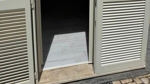 A doorway with a sliding shutter, a tiled floor, and a wall-mounted object. - RAGGIO DI SOLE: STUDIO APARTMENT JUST A STONE'S THROW FROM THE BEACH (Castiglione della Pescaia)