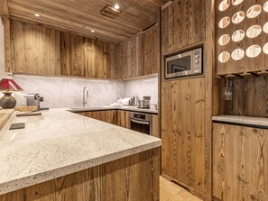 Une cuisine dotée de meubles en bois, d’un plan de travail en granit, d’un four à micro-ondes et d’un évier.