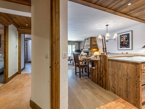 Ein raumhohes Holzgestell mit Essbereich, Kamin und moderner Leuchte.