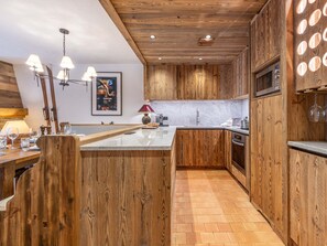 Une cuisine avec des armoires en bois, un plan de travail en marbre et un plafond en bois.