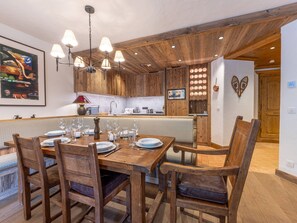 Mesa de madera con platos y vasos, rodeada de sillas.
