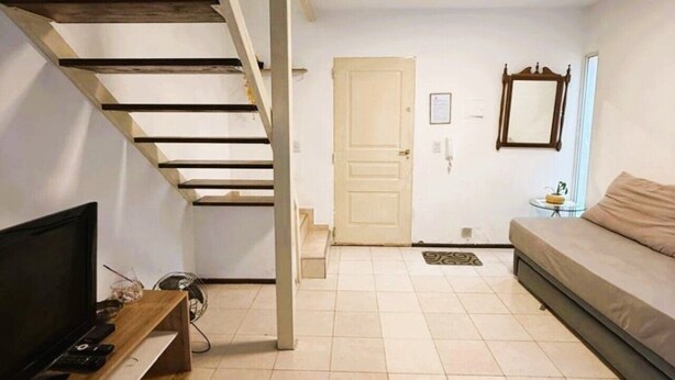Um apartamento moderno com escada de madeira, televisão de tela plana, sofá e uma porta.