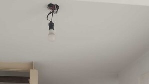 Um quarto com cama, porta, luminária pendente e chão revestido de azulejos.