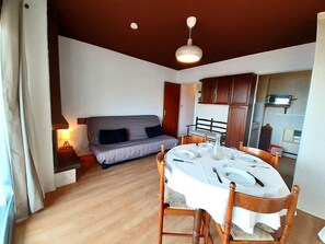 Ein gemütlicher Wohnbereich mit Esstisch für vier Personen, einer Couch, Holzschränken und einem Deckenventilator.