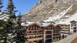 Eine mehrstöckige Lodge mit Holzfassade, vor einer schneebedeckten Berglandschaft und blauem Himmel gelegen.