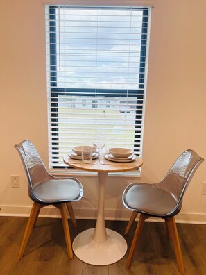 Ein Essbereich mit einem runden Tisch, zwei Stühlen und einem Fenster mit Jalousien.