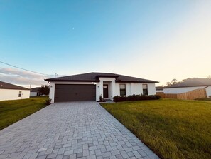 Ein modernes Einfamilienhaus mit gepflasterter Auffahrt, Garage und gepflegtem Rasen.