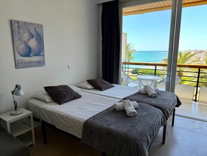A hotel room with two beds, a painting on the wall, and a balcony with a view of the sea. - Casa Ángeles - Terraza y vista al mar (Torremolinos)