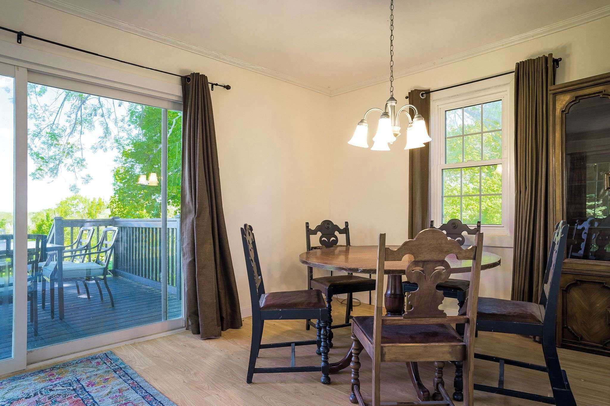A dining area with a table and chairs, a chandelier, and a view of the outdoors.