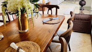 Ein Essbereich mit einem Holztisch, gewebten Tischsets und einer Blumenvase.