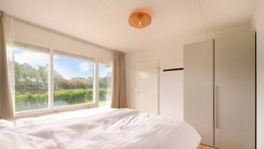 Un dormitorio con una cama grande, un armario y una ventana con vistas a zonas verdes.