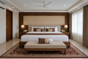 A hotel room with a large bed, two bedside tables with lamps, a ceiling fan, and a red patterned carpet.