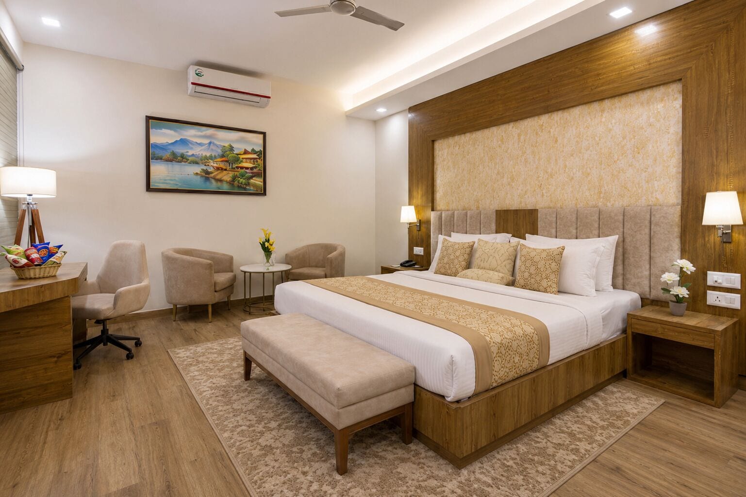 A hotel room with a large bed, two armchairs, a desk with a lamp, a small table with flowers, and a painting on the wall.