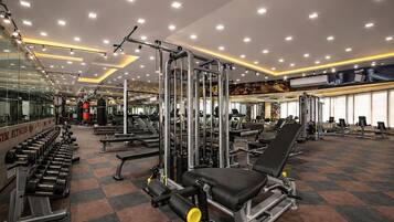 Un gimnasio con equipo de ejercicio diverso, espejos y piso de baldosas.
