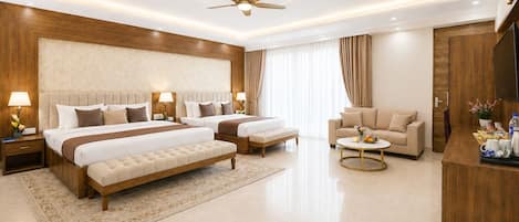 A modern hotel room with a large bed, a sofa, a coffee table, and a TV.