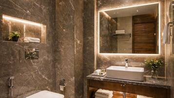 Un baño moderno con tocador de mármol, inodoro independiente, un espejo grande y zona de ducha.