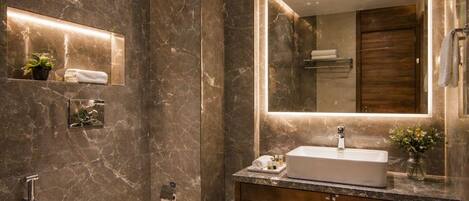 Un baño moderno con tocador de mármol, inodoro independiente, un espejo grande y zona de ducha.