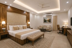 Ein Hotelzimmer mit einem großen Bett, einer Couch, einem Schreibtisch und einem Deckenventilator.