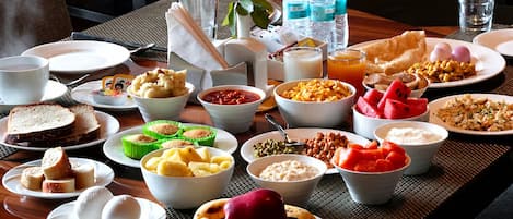 Un buffet de petit-déjeuner proposant une variété de plats, notamment des fruits, des céréales et des viennoiseries.