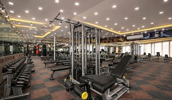 Een sportschool met diverse fitnessapparaten, spiegels en een betegelde vloer.
