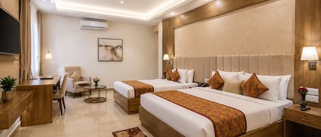 A hotel room with two beds, a desk, a chair, a TV, and a ceiling fan.