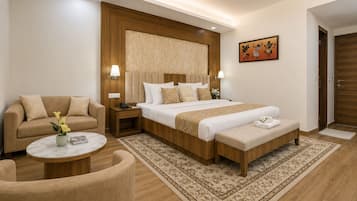 A hotel room with a bed, a sofa, a small table, and a decorative wall piece.