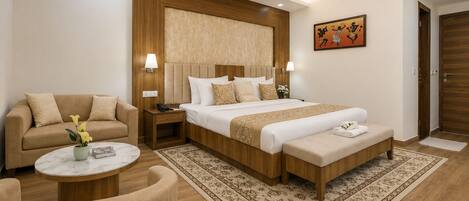 A hotel room with a bed, a sofa, a small table, and a decorative wall piece.