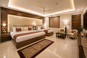 A modern hotel room with a large bed, a smaller bed, a seating area with a table, and a TV.