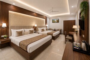 A hotel room with two beds, a desk, and a chair.
