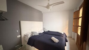 A bedroom with two beds, a ceiling fan, and a wooden wardrobe. - Castelo Silleria (Granada)