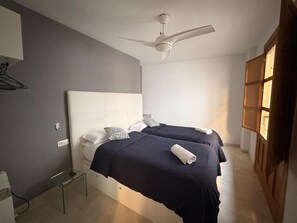 Un dormitori amb dos llits, un ventilador de sostre i un armari de fusta.