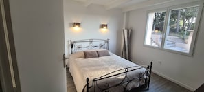 Une chambre à coucher avec un lit, deux lampes fixées au mur, une fenêtre et un grand lampadaire.