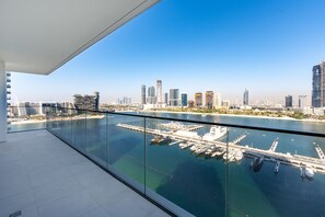 Ein Hochhaus mit Glasbalkon mit Blick auf eine Marina, in der Boote liegen, und eine Stadtansicht.