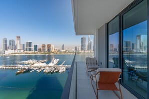 Ein Balkon mit zwei Stühlen und Blick auf einen Yachthafen mit Booten sowie auf eine Stadtansicht.