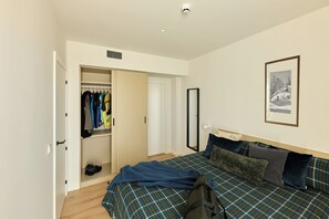 Un dormitorio con cama, armario, espejo y un cuadro en la pared.