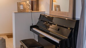 Piano, jonka yläpuolella on peili, sekä lamppu ja pieni penkki.