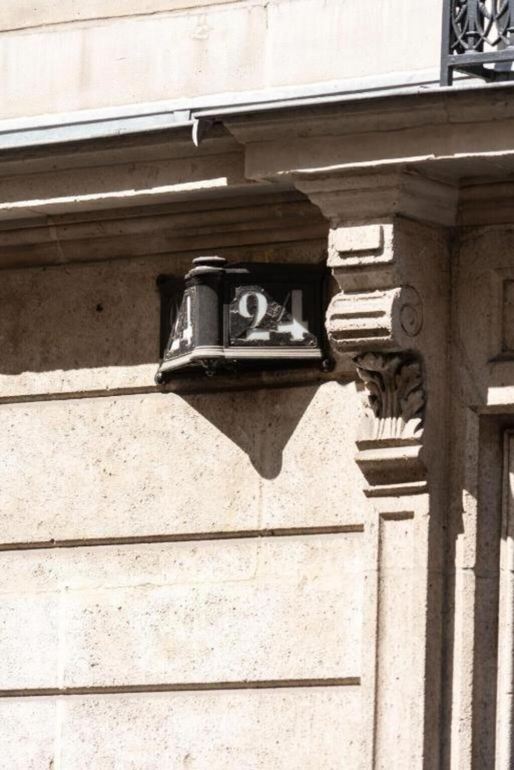 A building facade with a stone column and a black mailbox displaying the number 24.