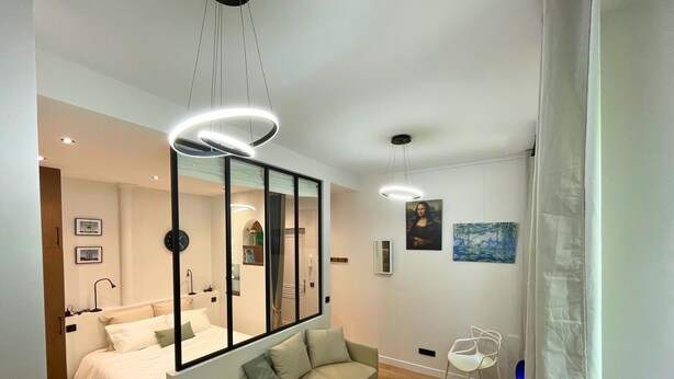 A modern bedroom with a bed, a sofa, a mirror, and a painting on the wall. - Comfortable & Peaceful Apartment, Latin Quarter - Newly Renovated (Paris)