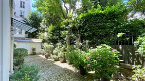 A courtyard with a cobblestone path, potted plants, and a metal fence. - Comfortable & Peaceful Apartment, Latin Quarter - Newly Renovated (Paris)