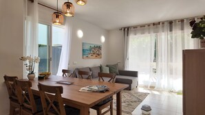 A dining area with a wooden table and chairs, a sofa, and a painting on the wall. - Apartment in El Verger, 800 metres from the sea, with garden and communal pool (El vergel)