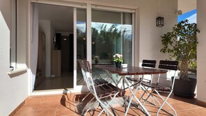 A patio with a table and chairs, a potted plant, and a sliding glass door leading to an interior space. - Apartment in El Verger, 800 metres from the sea, with garden and communal pool (El vergel)